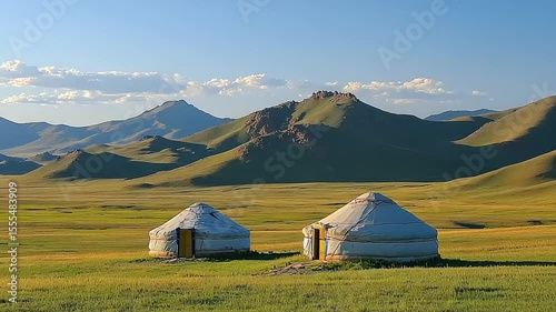 Yurts in a grassy valley with mountains in the background