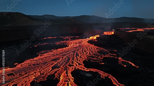 River of lava flowing toward mountains under dark blue evening sky
