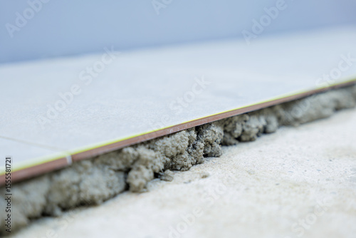 A detailed view of a gray tile securely laid on gray mortar, showcasing the evenness and professional finish of the flooring process.