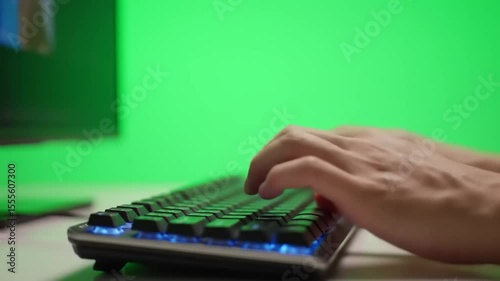 Close-up of a hand typing on a mechanical keyboard with a vibrant green background, ideal for tech themes
