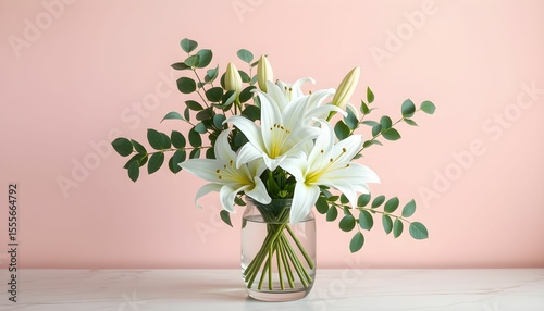 A bouquet of white lilies and eucalyptus in a clear glass vase against a soft pink background.