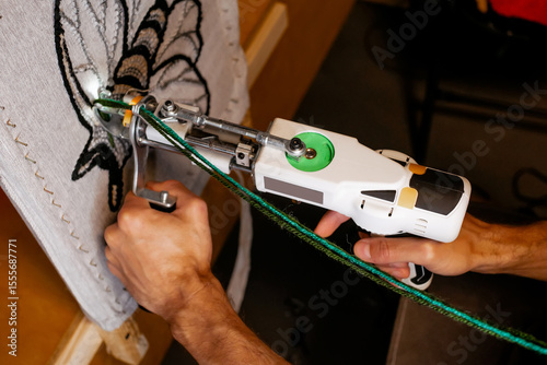 Cuadro en lienzo Close-up of a hand-held tufting gun being used to create a rug with green yarn,
