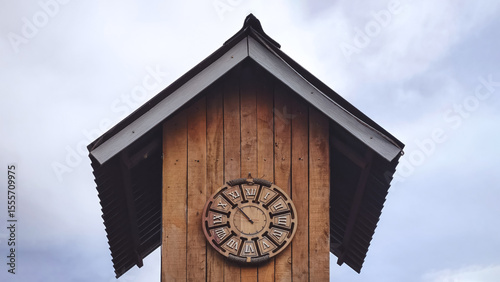 Rustic wooden clock tower under a cloudy sky evokes timeless rural charm and historical atmosphere