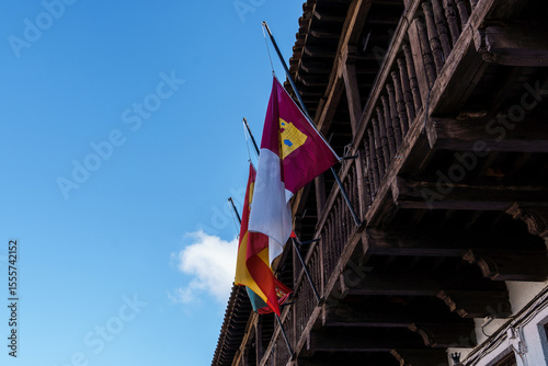 Flags hanging on medieval wooden balcony in the square of Spain in the old town of Consuegra, Toledo