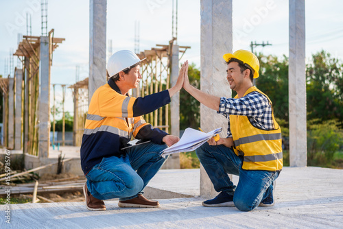 Obraz na plátne An elderly man and a middle-aged Asian man, both wearing hard hats and reflectiv