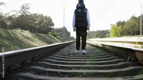 Sad boy walking on the railroad in a bad mood after school. Childhood bullying and depression.