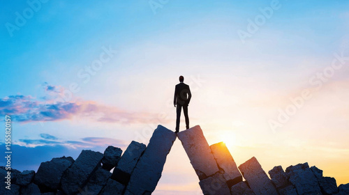 Business mindset resilience risk taking is essential for success, as shown by figure standing on rocky peak at sunset