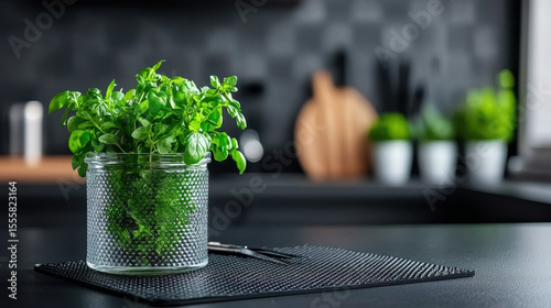 Fresh herbs in glass jar on kitchen counter, showcasing vibrant green leaves and modern aesthetic