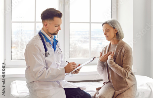 Doctor consulting female senior patient sharing symptoms, complaining, anxious, troubled about health. Old woman visiting clinic for medical care, discussing treatment plan, asking help, nervousness