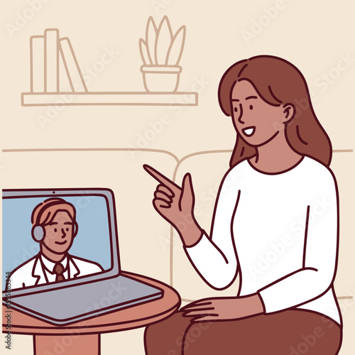 Dark-skinned woman points and talks to doctor on laptop screen during remote online medical consultation from home