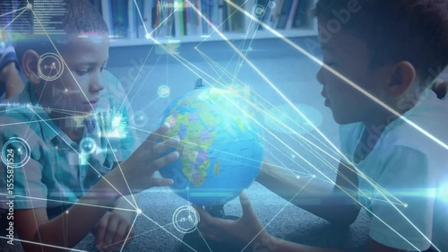 Two boys touching globe and rotating it in learning corner, displaying digital network connections