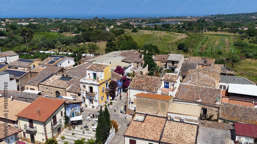 Obraz premium Borgo Parrini, Palermo, Sicilia, Italia - 06/15/2025: Case dipinte dell'antico Borgo detto anche la Barcellona di Partinico. Ripresa aerea con drone di Borgo Parrini, meta turistica della Sicilia.