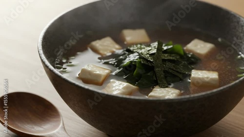 Miso Soup with Tofu and Seaweed: A close-up shot of a steaming bowl of traditional Japanese miso soup, featuring soft tofu cubes, delicate seaweed, all in a rich, flavorful broth. A spoon sits beside.