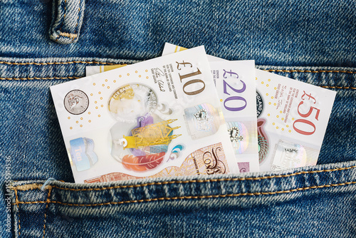 British pound banknotes in denim pocket. Ten twenty fifty pound notes visible in jeans. Concept of wealth savings or salary. Modern currency stored in everyday clothing. Budget or finance symbol.