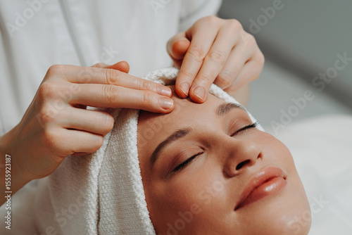 face massage, young attractive caucasian woman, beautiful relaxed lady with closed eyes smiling, white towel, spa therapist doing facial and head massage in beauty salon, skincare and bodycare concept