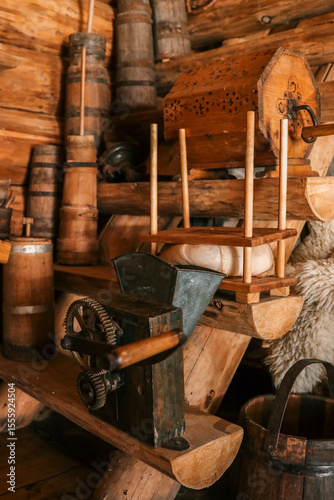 Rustic log-cabin shelf with antique hand-crank grain mill, wooden butter churns, decorated storage box and traditional dairy press in warm cottage light photo
