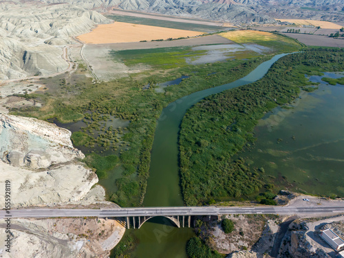 Nallihan Bird Sanctuary Ankara Turkey Aerial View of a Bridge Spanning a River Through Lush Landscape. High-angle, full shot of a bridge gracefully arching over a flowing river, weaving through divers