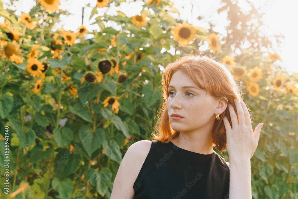 Elegant redhead woman wearing golden hoop earrings in sunflower field Elegant redhead woman wearing golden hoop earrings in sunflower field