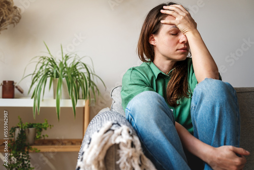 Stressed and tired young adult woman at home.