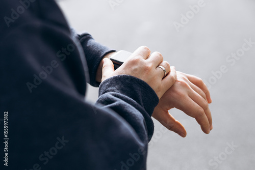 Close-up of male hand checking smartwatch outdoors. Modern wearable technology.