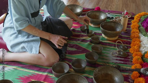 The girl's hands play on singing bowls sitting on the floor. Singing bowl playing ceremonies