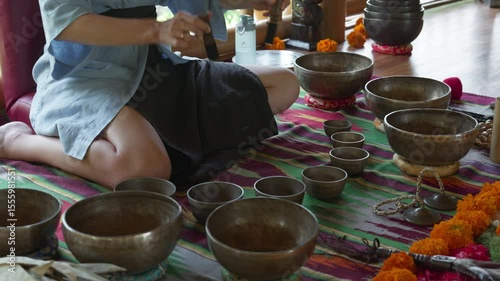 The girl's hands play on singing bowls sitting on the floor. Singing bowl playing ceremonies