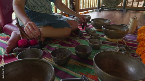 The girl's hands play on singing bowls sitting on the floor. Singing bowl playing ceremonies