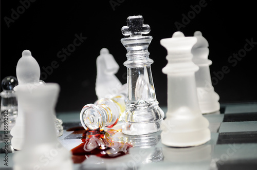Glass chess pieces on a board symbolize a corporate or political power struggle. Dramatic defeat, betrayal, or leadership failure.