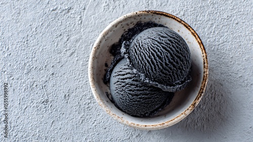Flat lay of black sesame ice cream, rich tones on white ceramic dish, artistic negative space