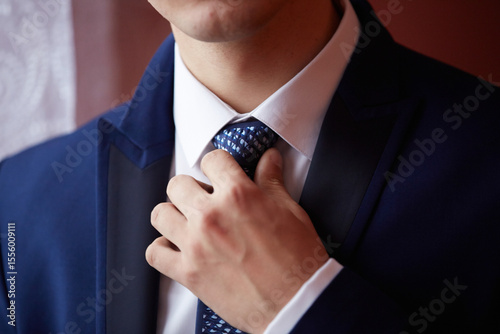 A man is getting ready to tie his blue tie