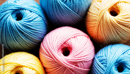 Several skeins of yarn in blue, yellow and pink colors arranged in a circle, close-up in studio with soft natural light