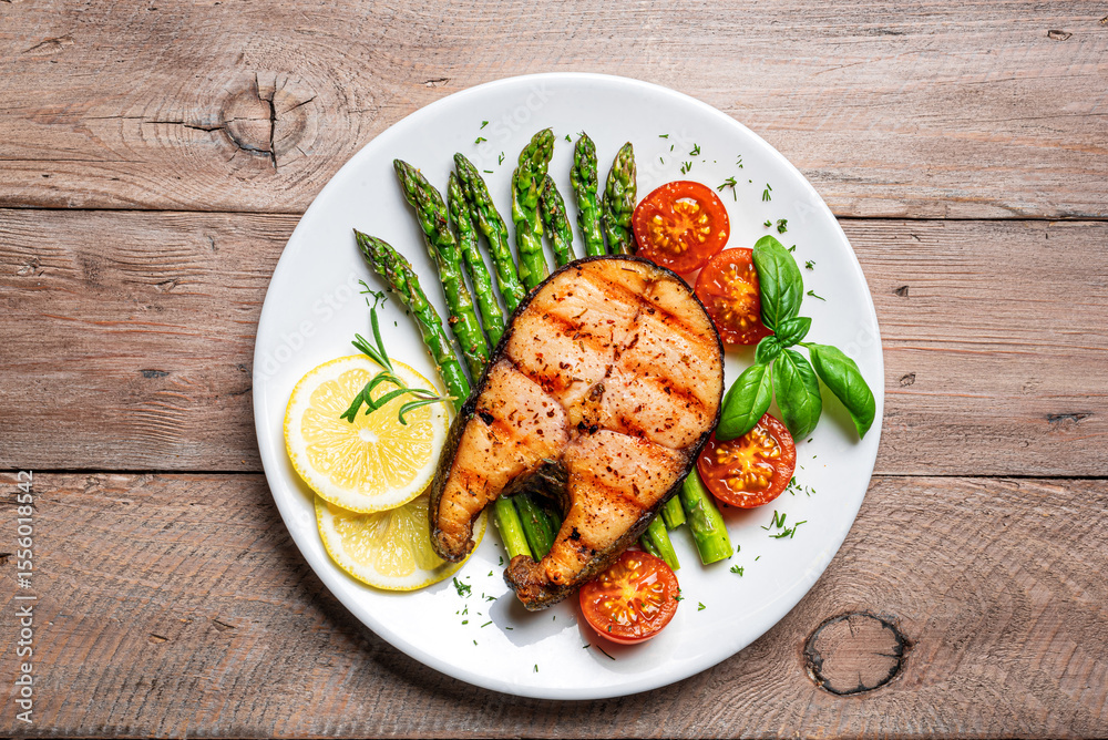 Grilled salmon steak with green asparagus, tomatoes and lemon slices Grilled salmon steak with green asparagus, tomatoes and lemon slices