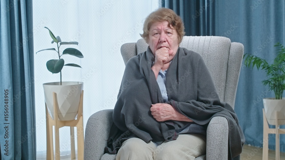 Fototapeta premium Mature woman in armchair feeling unhealthy and coughing, flu symptoms and treatment concept