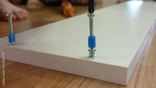 Close-up of screws being installed on a white wooden panel  
