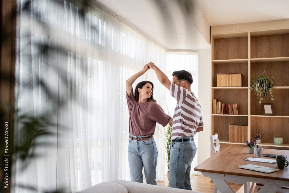 Fototapeta premium Happy couple dancing together in modern living room