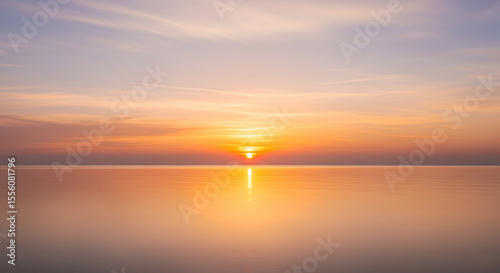 Calming sunset over peaceful ocean, pastel sky, golden reflections on smooth water. Perfect minimalist landscape background for relaxation and meditation content.