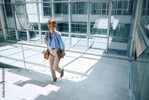 Happy Korean businesswoman walking upstairs in office.