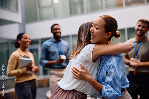 Female entrepreneurs embracing while celebrating their business success at work.