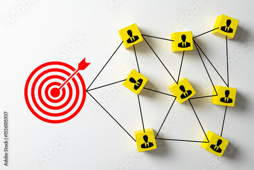Teamwork and business goal achievement concept.,A network of employee icons on wooden cubes all connected to a central target, representing collaboration,company objectives.