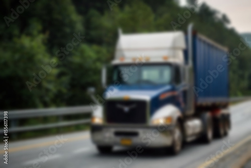 Blurry photo of container truck carrying large containers on highway with beautiful sunset.