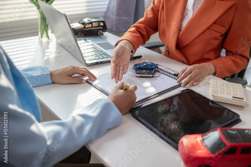 Asian businesswoman agreeing to sign a contract to buy a car from a car dealer for business use. Image of a businesswoman and a car dealer agreeing to sign a contract to buy a car from dealer.