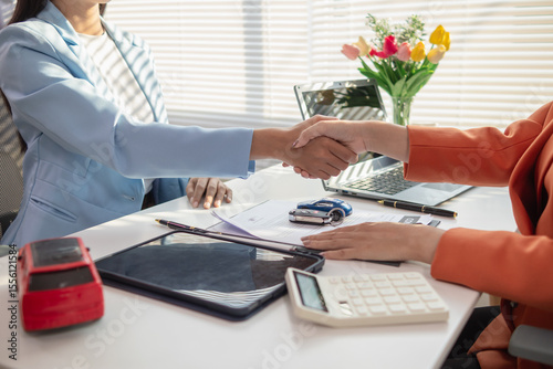 Asian businesswoman agreeing to sign a contract to buy a car from a car dealer for business use. Image of a businesswoman and a car dealer agreeing to sign a contract to buy a car from dealer.