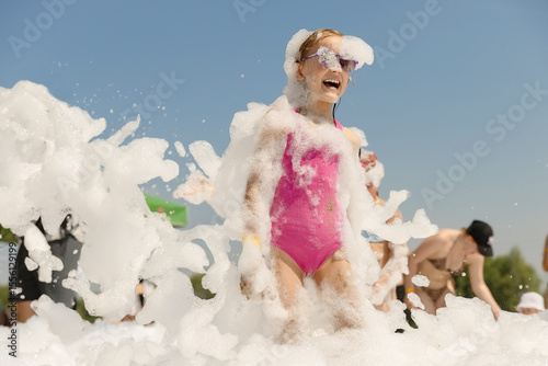 Cute little girl having fun at foam party.