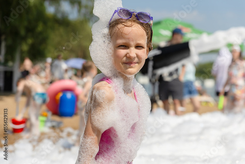Cute little girl having fun at foam party.
