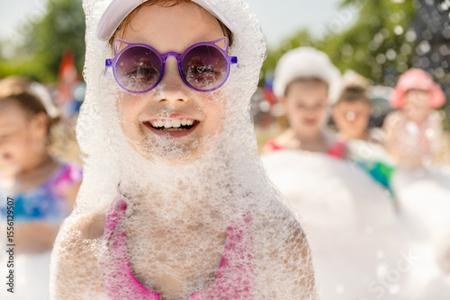 Cute little girl having fun at foam party, close-up, copy space.