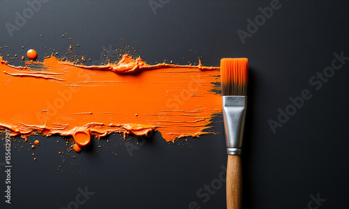 paintbrush with orange paint on a black background, creating a vibrant contrast between the two colors. 