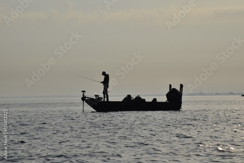 Angler fishing at sunrise in a boat