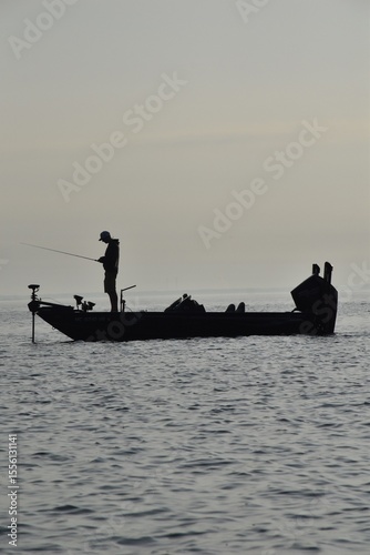 Angler fishing at sunrise in a boat
