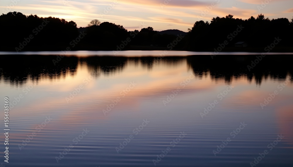 Obraz premium the image shows a tranquil landscape during what appears to be dawn or dusk, in the foreground, there is a calm body of water, possibly a lake or pond