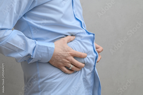 Wall Mural Slim man holds his hands to his swollen belly, severe painful indigestion, abdom